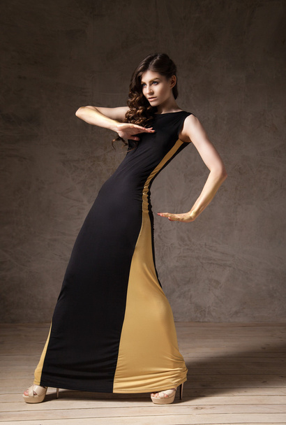 fashion model with wavy hair wearing long dress and gesturing by arms - Fotó, kép