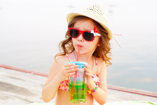 little girl drinking sparkling water on the pier - Φωτογραφία, εικόνα