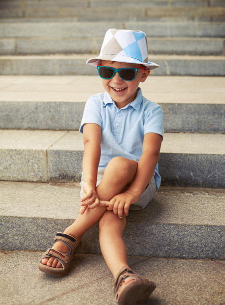 Napszemüveg és kalap ül és laughin kisfiú portréja - Fotó, kép
