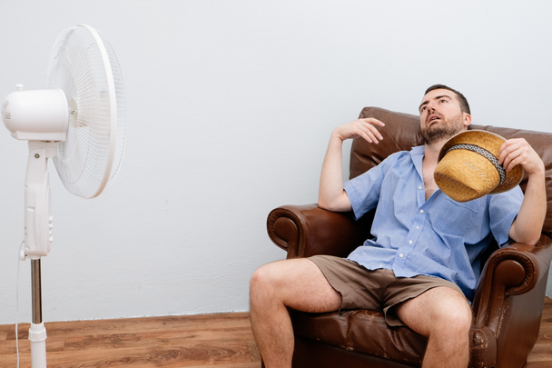 Hombre ruborizado sintiéndose caliente delante de un ventilador
  - Foto, imagen