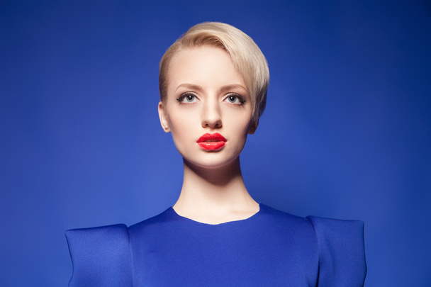 Pretty blonde model with fashion hairstyle against of blue backgound - Fotoğraf, Görsel
