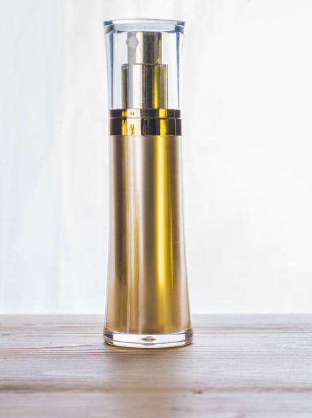 zlaté kosmetické láhev na dřevěný stůl - Fotografie, Obrázek