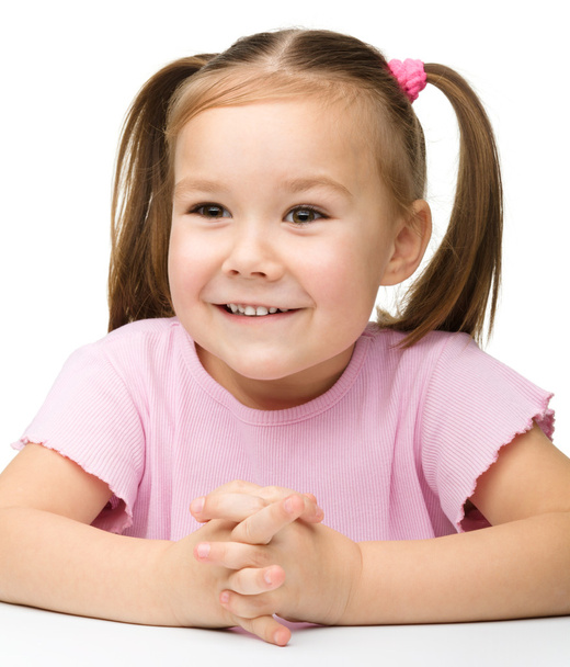 Happy little girl sits at a table and smile - Photo, Image