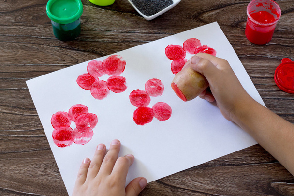 das Kind zeichnet auf Papier, indem es die Druckkartoffeln verwendet und - Foto, Bild