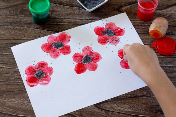 Рисуя на бумажных маках, ребенок рисует маковые семена. Клей, краска
,  - Фото, изображение