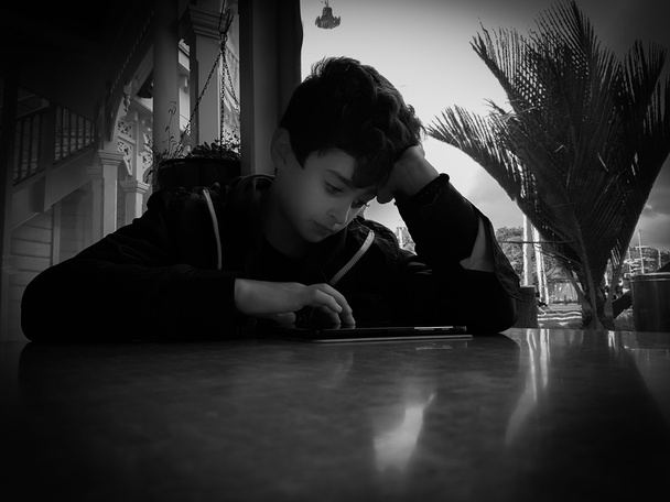 Grainy effect b & w boy at table. - Photo, Image