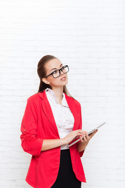 Businesswoman use tablet computer touch screen look up to copy space wear red jacket glasses happy smile - 写真・画像