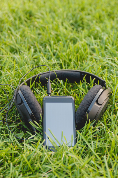 Black Smartphone and Headphones on the Green Grass - Foto, Bild