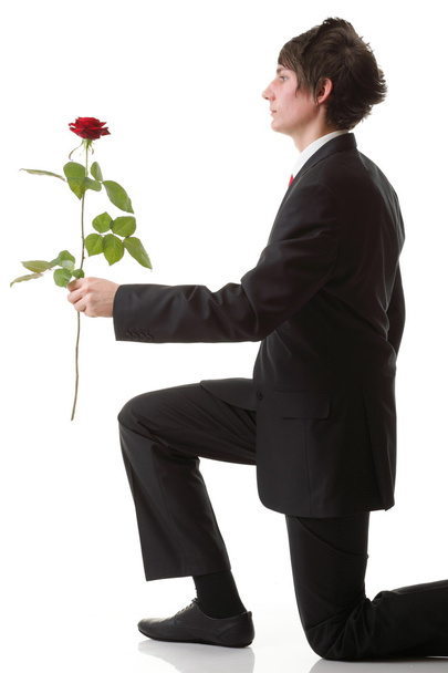 fiatal férfi bemutató egy piros virág rózsa elszigetelt - Fotó, kép