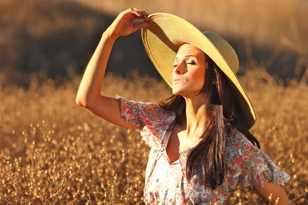 Yaz şapka ile bir alanda güzel bir kadın - Fotoğraf, Görsel