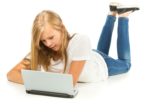 Giovane ragazza sdraiata sul pavimento utilizzando il computer portatile su sfondo bianco
 - Foto, immagini