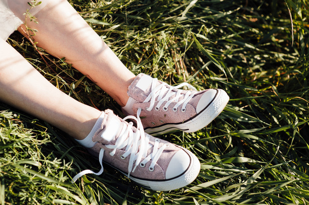 purple sneakers on girl legs at grass - Valokuva, kuva