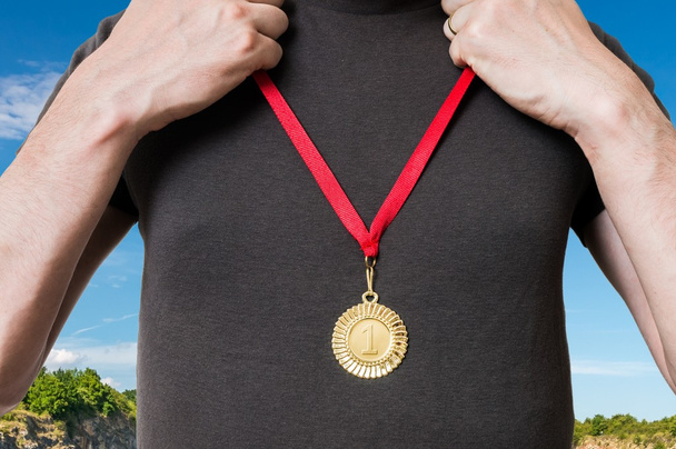Kampioen of winnaar zet gouden medaille op zijn borst. - Foto, afbeelding
