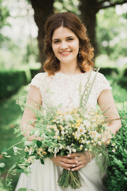 The bride holding bouquet of flowers in park. Wedding - 写真・画像