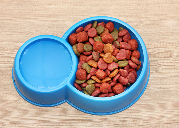 Dry dog food and water in blue bowl on wooden background - Фото, изображение