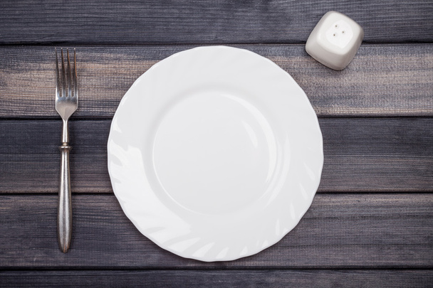 empty plate, fork and salt shaker on wooden table, top view - Photo, image