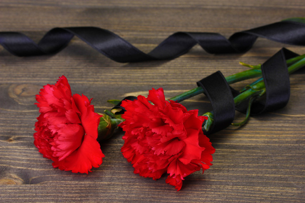 Carnations and black ribbon on grey wooden background - Fotografie, Obrázek