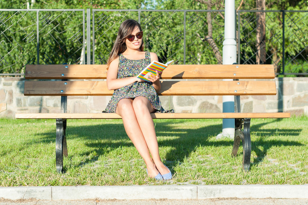 hübsche Dame sitzt auf Bank und liest - Foto, Bild