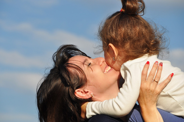Ευτυχισμένη μητέρα που αγκαλιάζει την κόρη της ενάντια στον ουρανό - Φωτογραφία, εικόνα