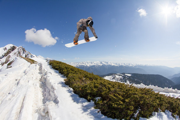 Snowboarder springt hoog in de bergen. - Foto, afbeelding