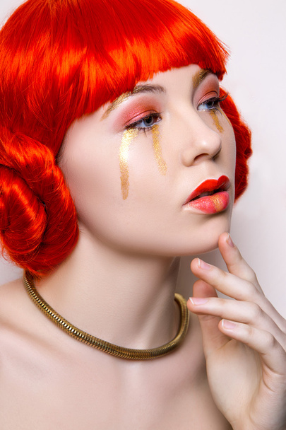 Frau in rot-goldener Mode geschminkt und rotes Haar auf weißem Hintergrund auf einem Studiofoto. Kunst-Schönheitsfoto - Foto, Bild