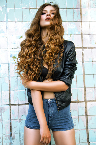 fashion model with long curly hair wearing leather jacket posing - Fotoğraf, Görsel