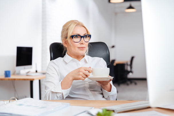 Femme d'affaires buvant du café avec ordinateur au bureau
 - Photo, image