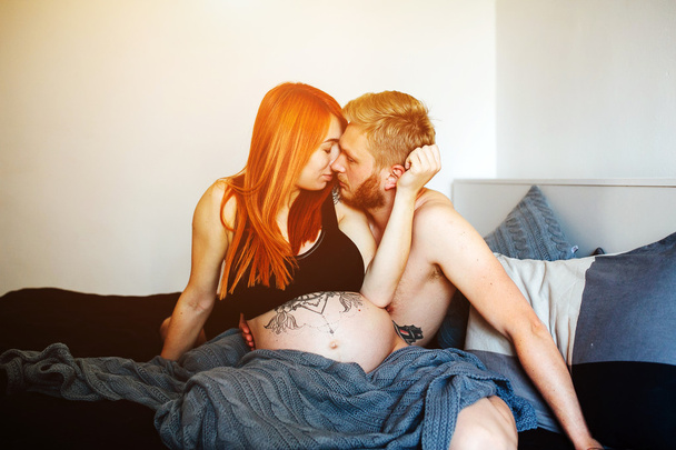 Zwangere vrouw en man liggend op een bed - Foto, afbeelding