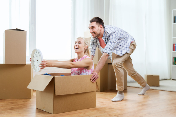 couple with cardboard boxes having fun at new home - 写真・画像