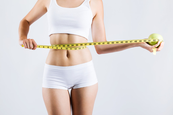 Woman measuring her slim body. Isolated on white background. - Zdjęcie, obraz