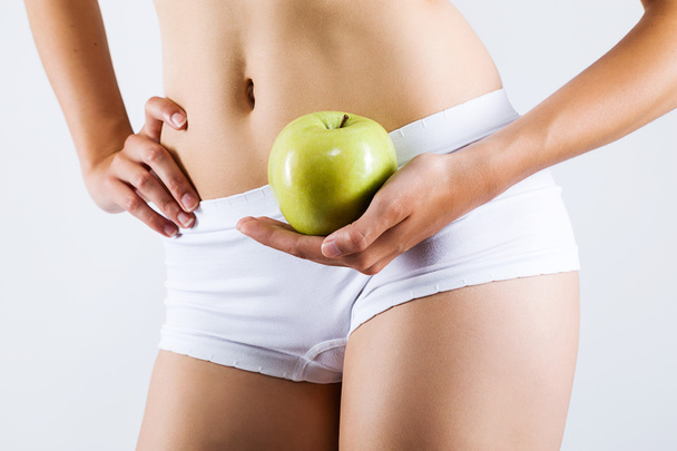 Beautiful young woman in white underwear holding green apple. - Photo, image