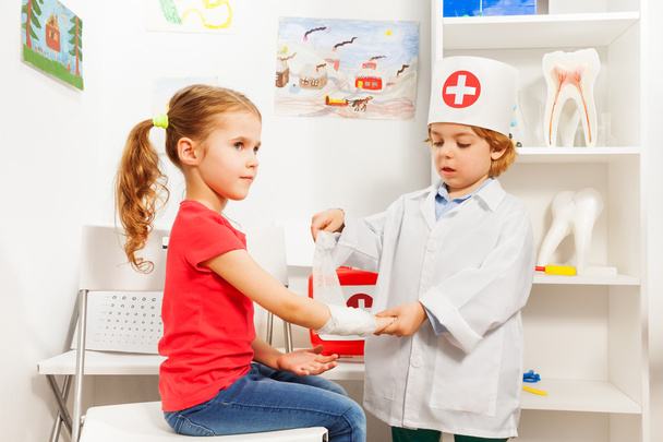 pediatrician doctor bandaging girl's arm - Фото, зображення
