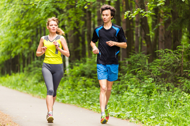 Couple running outdoors. Woman and man runners jogging together outside in full body length. - Photo, Image