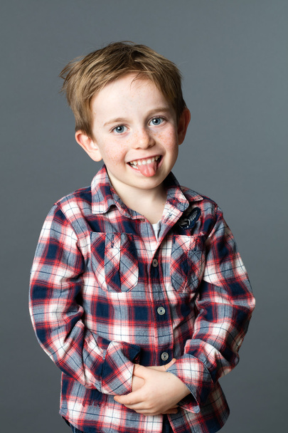 smiling shy young boy sticking out his tongue for wellbeing - Photo, Image