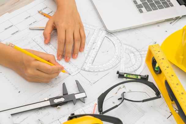 Hand over Construction plans with yellow helmet and drawing tool - Photo, image