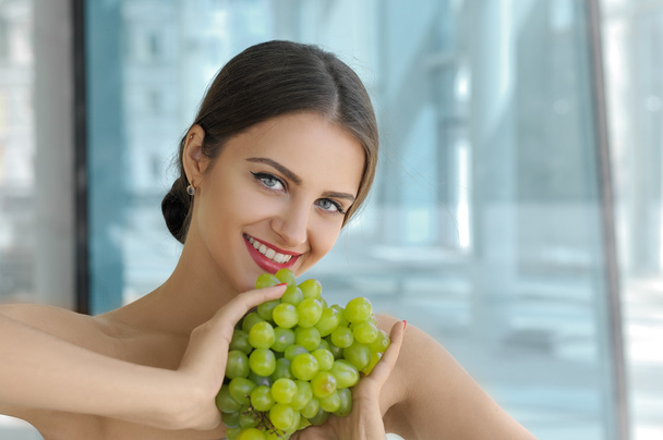 Girl is holding a bunch of ripe grapes in her hands - Foto, imagen