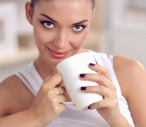 Portrait of young beautiful woman with a cup on sofa at home - Photo, image