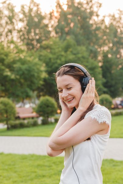Young Caucasian Brunette Woman with Headphones Outdoors - Photo, Image