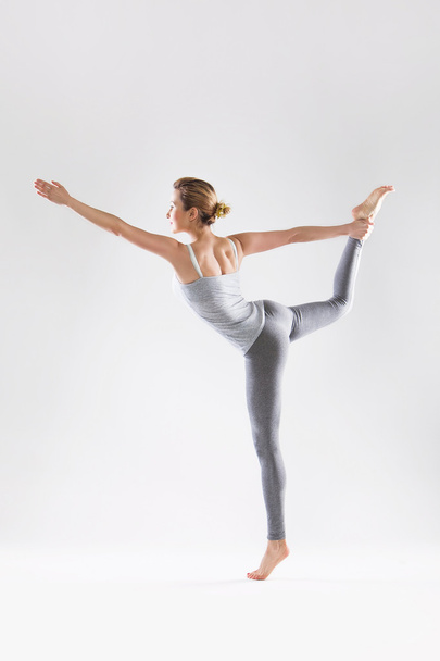 Beautiful young woman doing yoga on a gray studio background - Fotografie, Obrázek