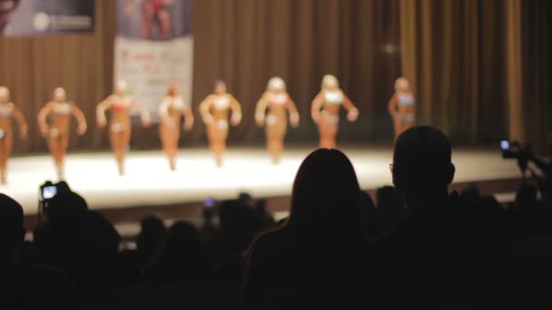Defocused lineup γυναικεία πρότυπα καταλληλότητας δείχνει μυώδες σώμα στη σκηνή - Πλάνα, βίντεο