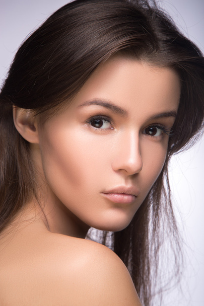 Closeup portrait of beautiful girl with clear healthy skin. Looking at the camera over shoulder. perfect fashion model studio photo - Photo, image
