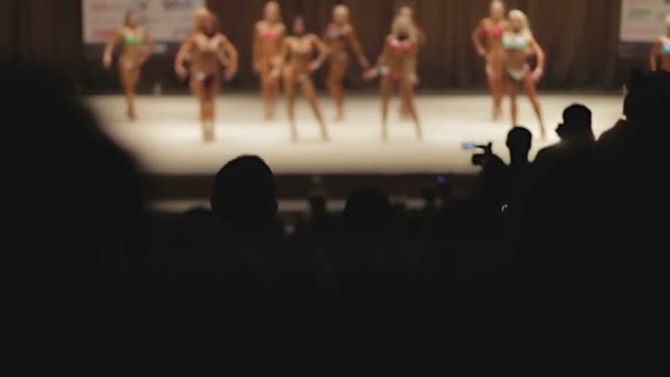 Silhouette di molte persone che guardano sexy bodybuilders femminile line-up sul palco
 - Filmati, video