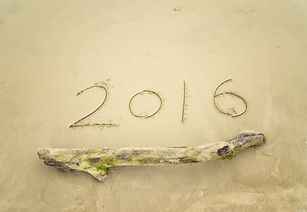 Vuosi 2016 käsin kirjoitettu valkoisella hiekalla meren edessä
 - Valokuva, kuva