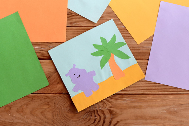 Mutlu su aygırı ve palmiye ağacı, ahşap bir masa üzerine renkli kağıt yaprak kağıt kartı. Anaokulu aktivite çocuklar için sanat ve el sanatları. Eğlenceli çocuk arka plan  - Fotoğraf, Görsel