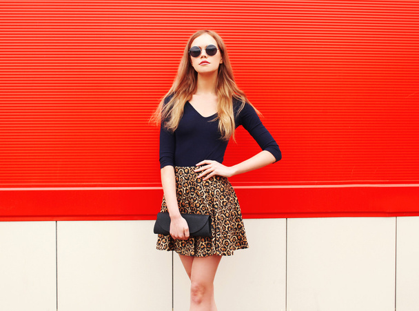 Fashion beautiful woman in leopard skirt sunglasses handbag clut - 写真・画像