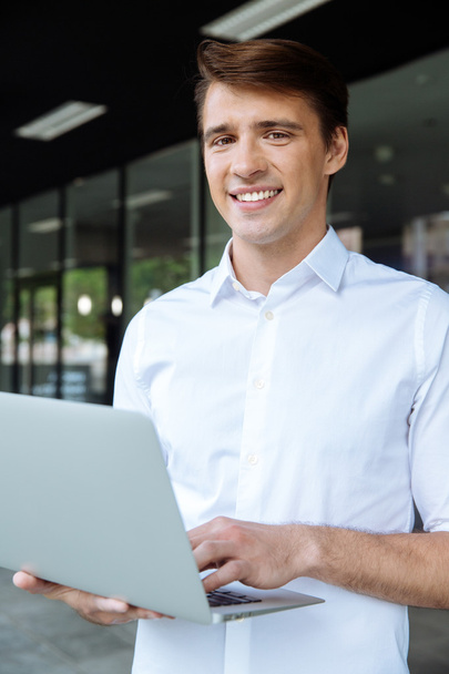 Businessman standing and working with laptop - Zdjęcie, obraz