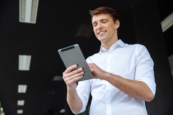 Веселий бізнесмен стоїть на відкритому повітрі і використовує планшет
 - Фото, зображення