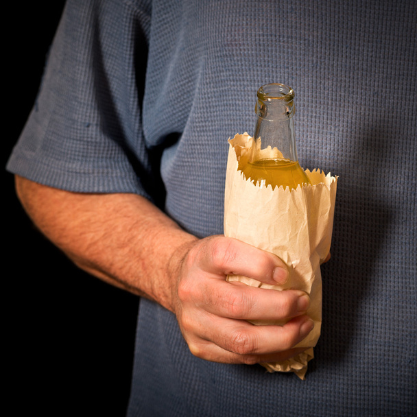 drinker holds a bottle in the paper bag - Фото, изображение