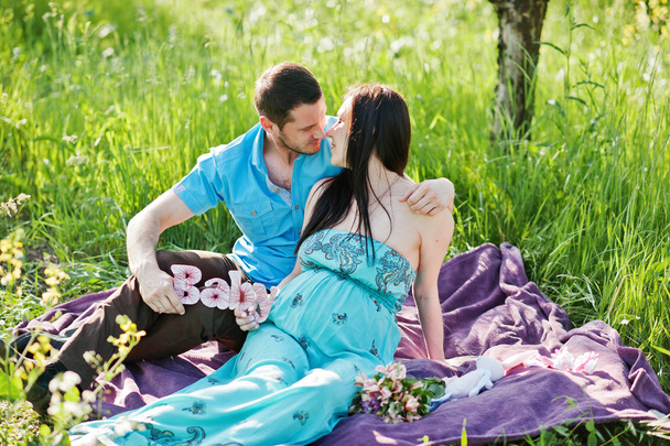 Happy pregnant couple at turquoise dress on the garden - Foto, immagini