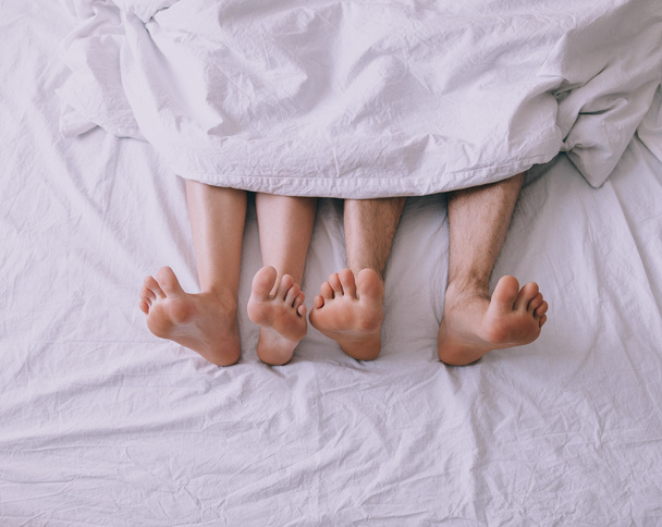 Feet of couple side by side in bed - Foto, afbeelding